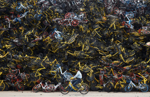 A worker rides a shared bicycle past piled-up shared bikes at a vacant lot in Xiamen, Fujian province, China December 13, 2017. Picture taken December 13, 2017. REUTERS/Stringer  ATTENTION EDITORS - THIS IMAGE WAS PROVIDED BY A THIRD PARTY. CHINA OUT.     TPX IMAGES OF THE DAY - RC16B19B1FA0